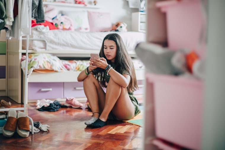 Una adolescente utiliza un dispositivo móvil en casa.