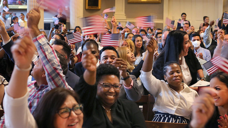 Personas recién naturalizadas como ciudadanos de EE.UU. ondean banderas durante una ceremonia