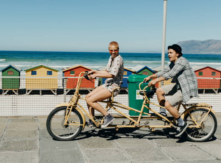 Young couple riding a tandem bicycle on a boardwalk