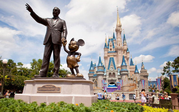 A statue of Walt Disney and Mickey Mouse sits in front of Cinderella's Castle at Magic Kingdom at Disney World.