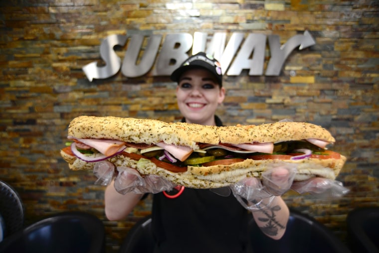 A Subway staff member holding a footlong sandwich. Picture: Scott Bairstow/Alamy