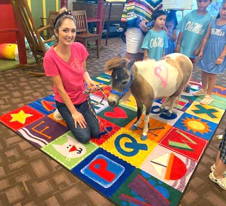 A volunteer poses with a pony inside El Progreso Memorial Library. The pony is house trained, thankfully.