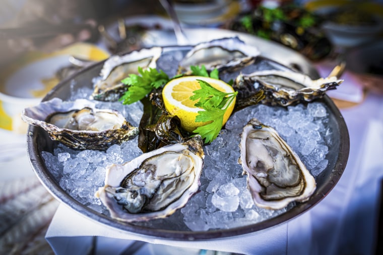 A half dozen fresh oysters are served with lemon in bowl with plenty of ice.