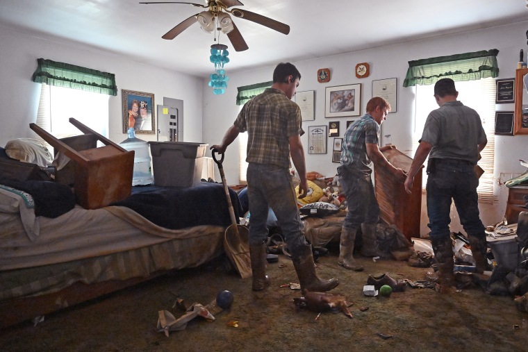 Volunteers from the local Mennonite community clean flood-damaged property Saturday at a house at Ogden Hollar in Hindman, Ky. 