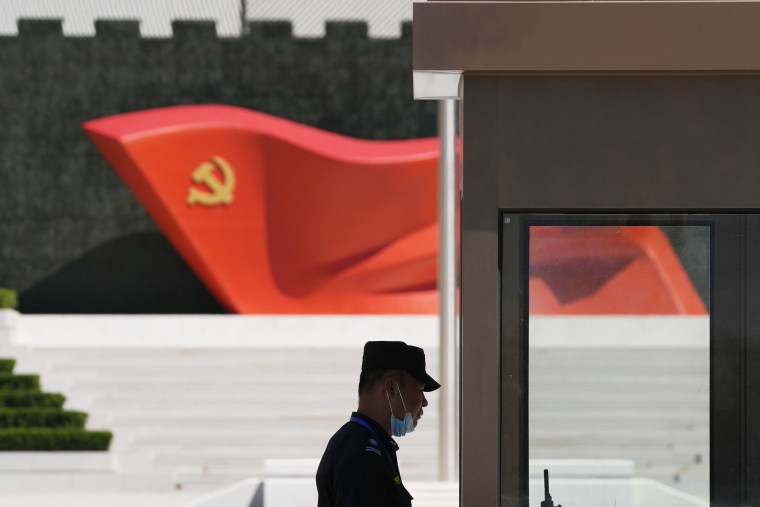 A security guard stands near a sculpture of the Chinese Communist Party flag