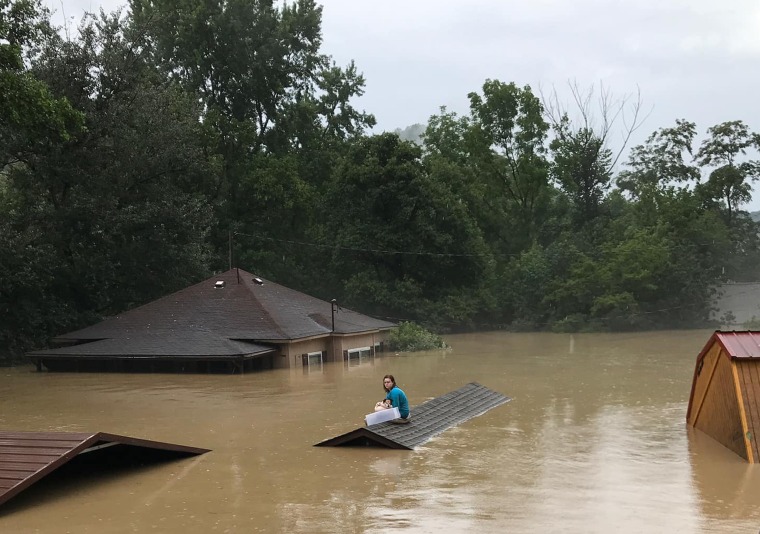 Chloe Adams sits on the roof of a storage facility with her dog, Sandy, as she waits to be rescued after flooding in Whitesburg, Ky.