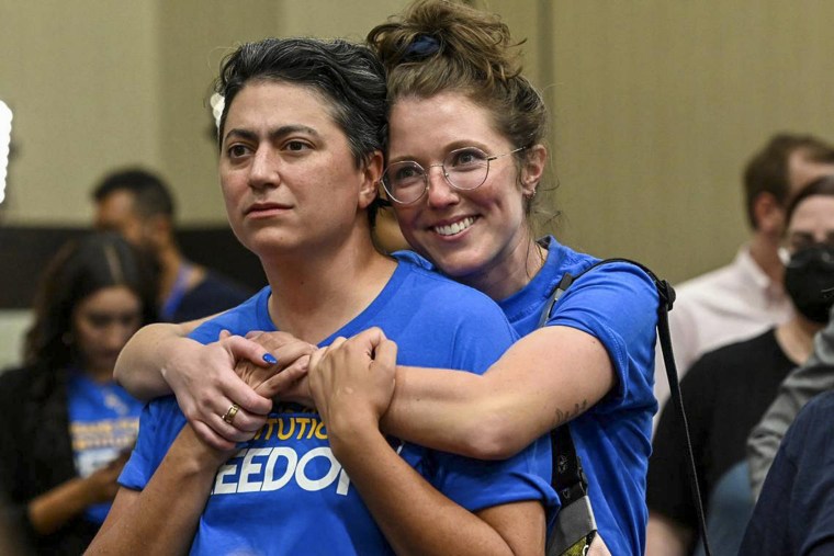 Image: Iman Alsaden, Chief Medical Officer for Planned Parenthood Great Plains, and Kelsey Rhodes  hug as they celebrate a victory at the polls in Overland Park, Kansas, on Aug. 2, 2022.