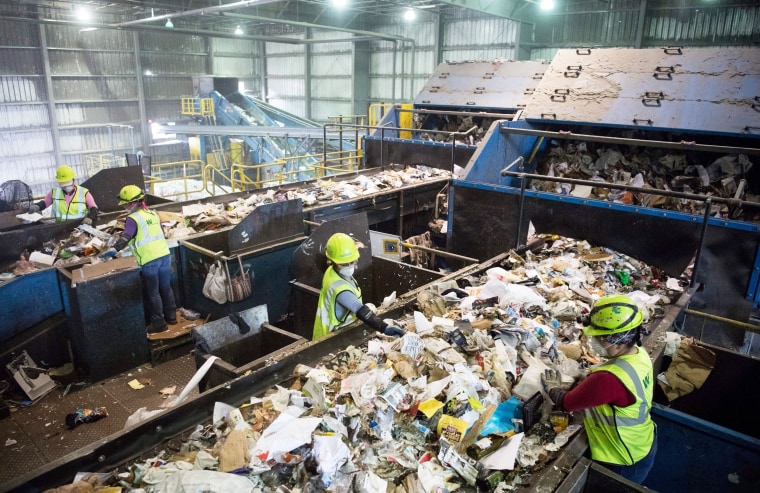 Workers sort recycling material at the Waste Management Material Recovery Facility
