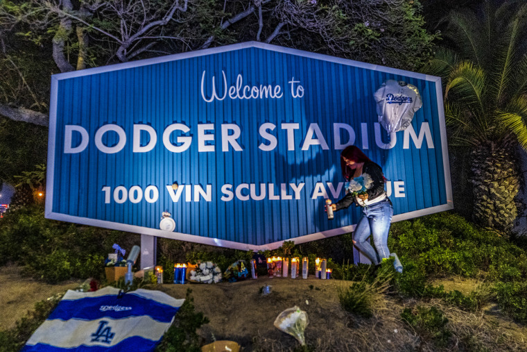 Image: Los Angeles Dodgers fans pay their respects to broadcaster Vin Scully next to a street sign bearing his name at the entrance to Dodger Stadium in Los Angeles, Calif. on  Aug. 2, 2022.