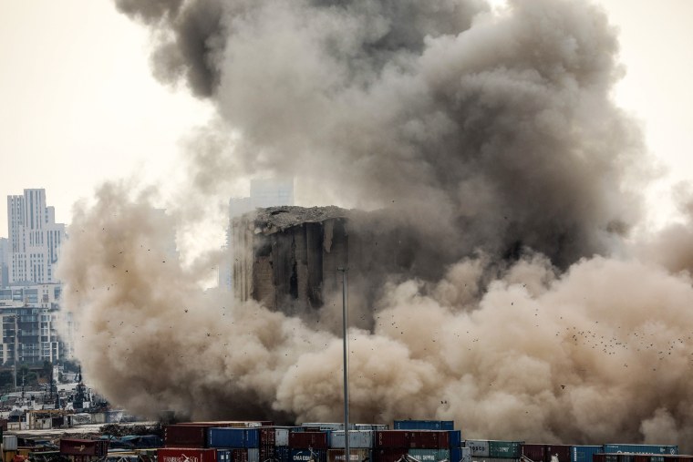Heavy dust rises as part of the grain silos in the port of Beirut collapses, due to an ongoing fire since the beginning of last month, on Aug. 4, 2022.