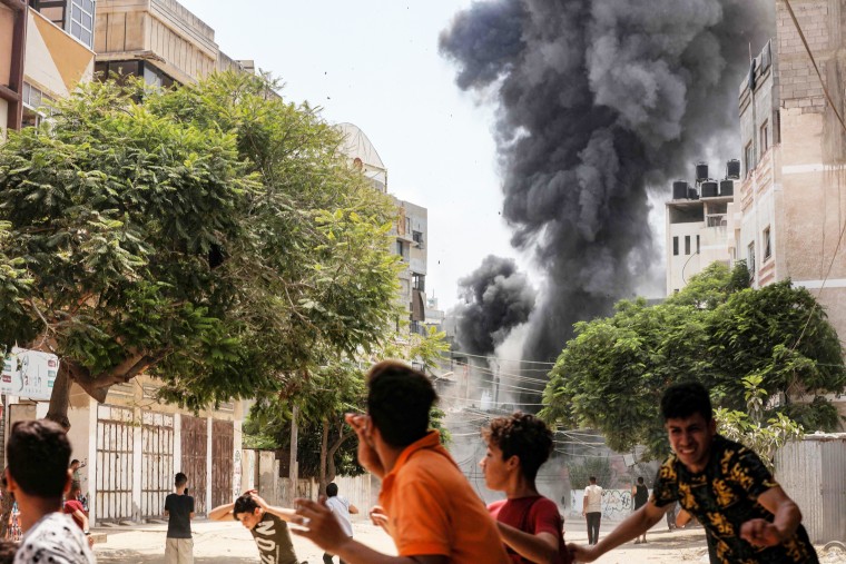 People run for cover during Israeli airstrikes in Gaza City