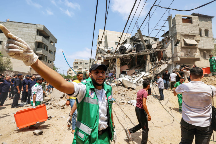 A paramedic warns people at the site of an Israeli airstrike in Gaza City