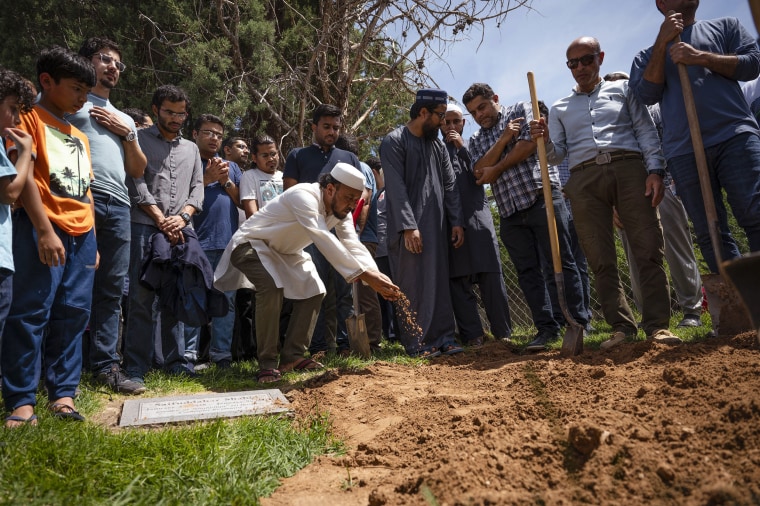 Image: People sprinkle dirt over the grave of Muhammad Afzaal Hussain, 27, at Fairview Memorial Park in Albuquerque, N.M., on Aug. 5, 2022.