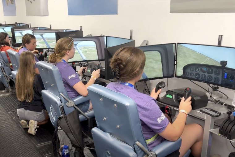 A group of young women from the EAA Girlventure Camp use flight simulators.