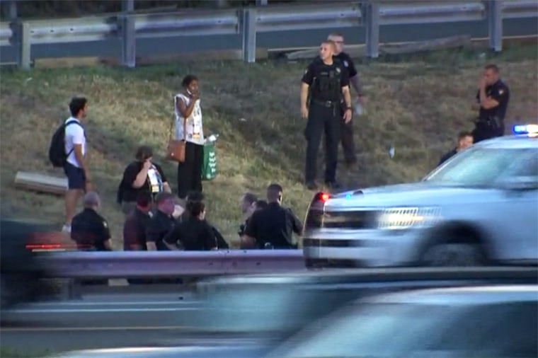 Civilians and police stand together along an area of the New Jersey Turnpike after a bus crash Tuesday.