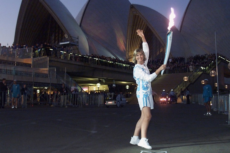 Olivia Newton-John holds the Olympic torch in front of Sydney Opera House