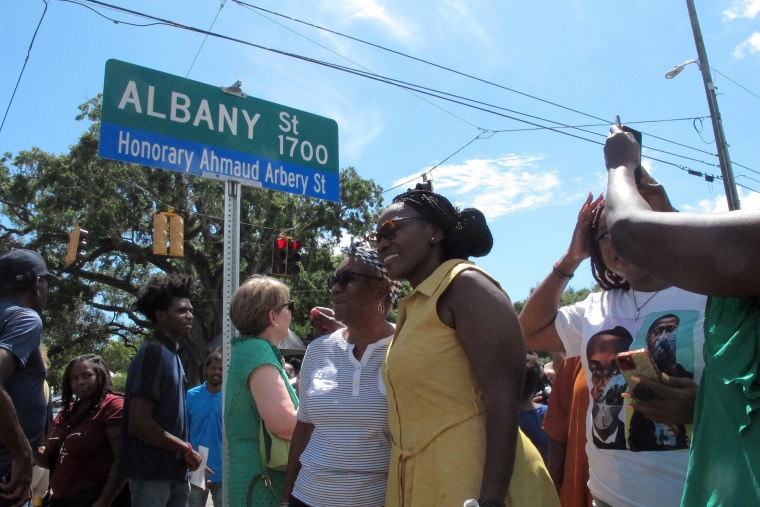 Image: Wanda Cooper-Jones, center in yellow dress, poses for photos with supporters beneath a new street sign honoring her son, Ahmaud Arbery, at the unveiling on Aug. 9, 2022, in Brunswick, Ga.
