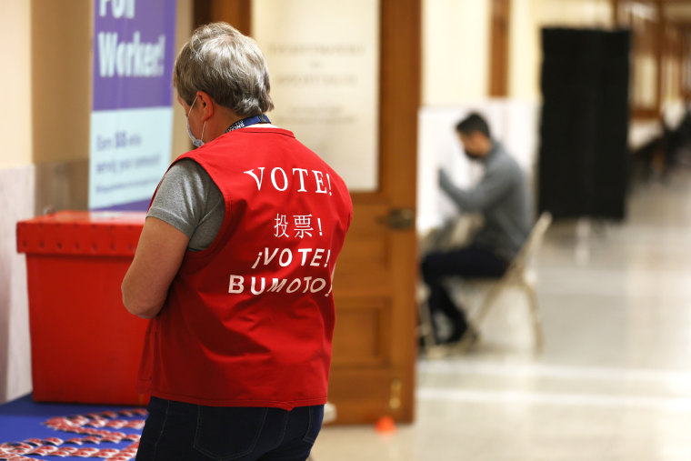 A poll worker wears a vest adorned with the word "vote"