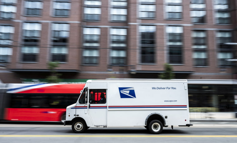 Image: A postman drives a United States Postal service mail delivery truck through Washington, D.C. on August 13, 2021.