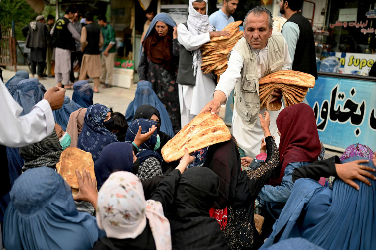 Image: A man distributes free bread during the holy fasting month of Ramadan in front of a bakery in Kabul on April 10, 2022.