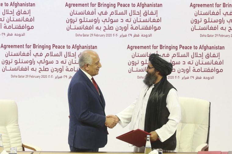 Then-U.S. peace envoy Zalmay Khalilzad, left, and Mullah Abdul Ghani Baradar, the Taliban's top political leader, shake hands after signing an agreement in Doha, Qatar, on Feb. 29, 2020,