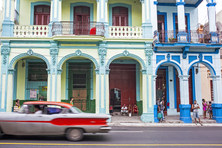 A car moves past residents in Centro Habana, La Habana, Cuba, on Oct. 23, 2015.