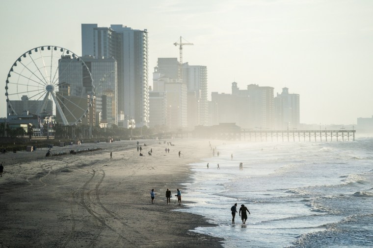 People walk along the beach the morning of May 29, 2021 in Myrtle Beach, S.C.