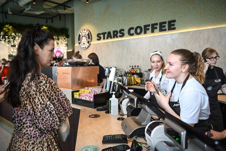 Image: A visitor speaks with employees at the newly-opened Stars Coffee cafe in Moscow, on August 19, 2022.