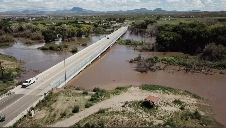 People drive over a bridge in Duncan, Ariz., following a flooding.