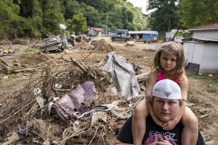 Image: Tatyn Skidmore  carries Brelyn Hays on his shoulders outside their home in the Upper River Caney community of Lost Creek, Ky., on Aug.18, 2022.