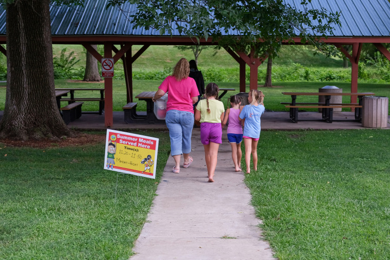 Image: Children follow as Christina Pinkerton and Shannon Bundridge take  food for the Summer Eats to the picnic area  in Kirksville, Mo., as on Aug. 16, 2022.