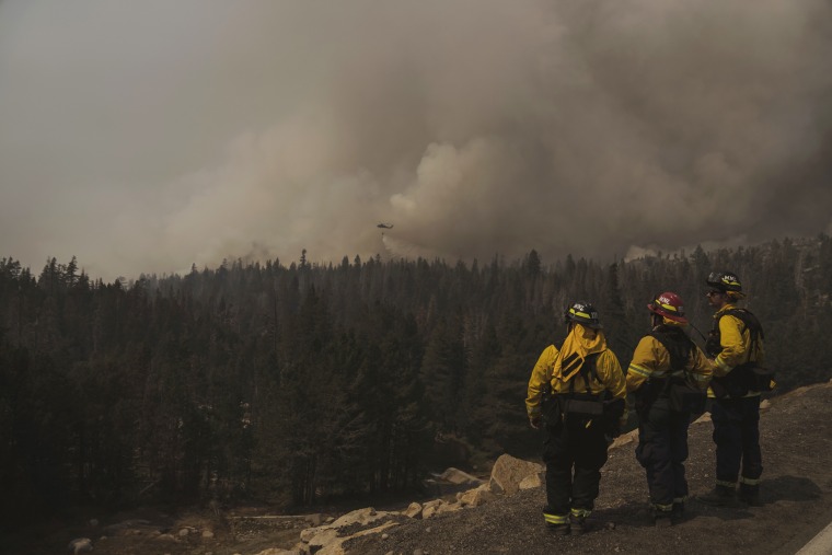 Firefighters watch as a helicopter drops water during the Caldor Fire in Kirkwood, Calif., on Sept. 2, 2021.