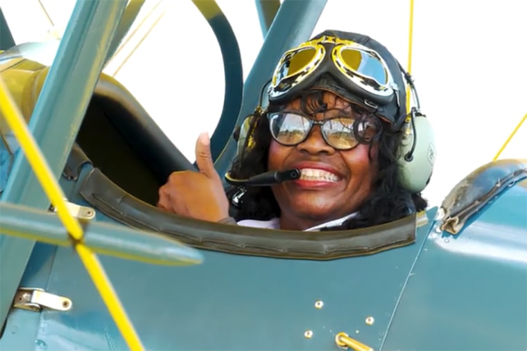 Gigi Coleman gestures as she prepares to take a flight in EAA’s 1929 TravelAir biplane at the EAA Aviation Museum’s Pioneer Airport in Oshkosh, Wis., in June 2021.