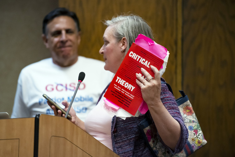 Image: Myra Brown holds up a book about Critical Race Theory as she speaks during the “Public Comment” portion of  a Grapevine-Colleyville Independent School District school board meeting in Grapevine, Texas, on  Aug. 22, 2022.