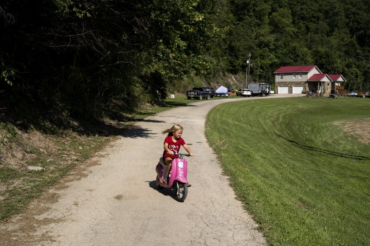 Image: Sailer Noble, 6, rides her electric bike from the camper she and parents have been staying in on Aug. 19, 2022 near Jackson, Ky., since their house was damaged in the flood.