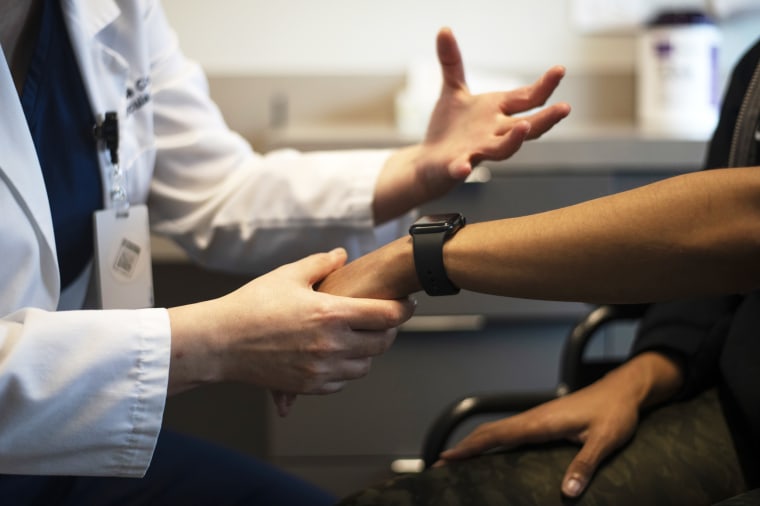 A doctor hold a patient's wrist during a long covid examination