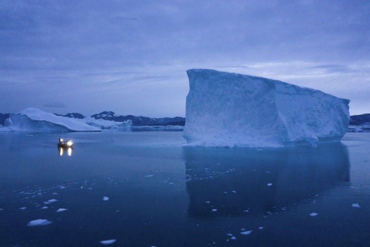 Image: A boat navigates at night next to large icebergs in eastern Greenland on Aug. 15, 2019.