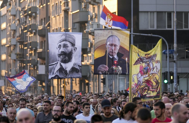 People hold up images of Russian President Vladimir Putin and controversial Serb World War II leader Gen. Dragoljub Draza Mihailovic, left, during a protest against the international LGBT event EuroPride in Belgrade, Serbia, on Aug. 28, 2022.
