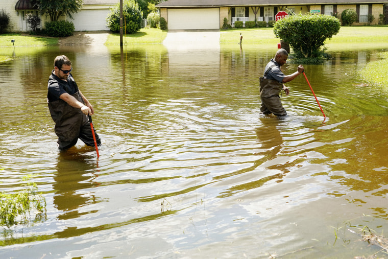 Hinds County Emergency Management Operations deputy director Tracy Funches, right, and operations coordinator Luke Chennault, wade through flood waters in northeast Jackson, Miss. on Monday, as they check water levels.