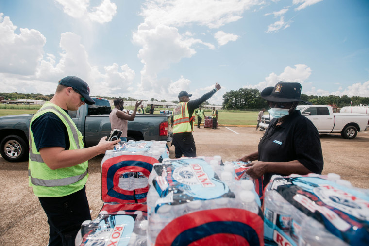 Volunteers and members of the fire department distribute water to local residents at Hawkins Field Airport in Jackson, Miss., on Aug. 30, 2022.
