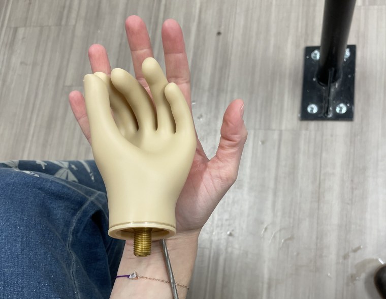 A tiny, greenish-tinged prosthetic hand resting perfectly inside Chloé’s palm.