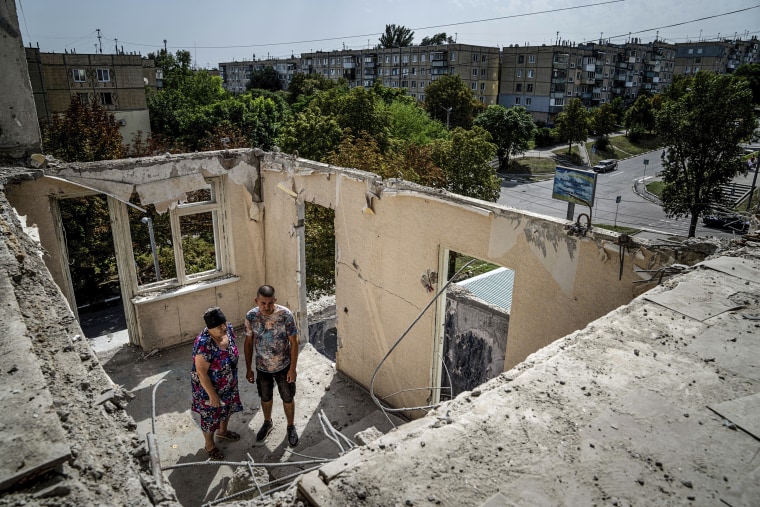 Image: Widow Liudmyla Shyshkina, 74, and her son Pavlo Shyshkin, 46, stand at their apartments house, which was destroyed after Russian bombardment of residential area in Nikopol, across the river from Ukraine's main nuclear power plant, in Ukraine, on Aug, 22, 2022.