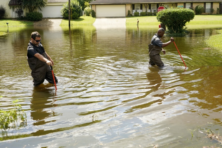 El subdirector de Operaciones de Gestión de Emergencias del Condado de Hinds, Tracy Funches, a la derecha, y el coordinador de operaciones Luke Chennault, vadean las aguas de la inundación en el noreste de Jackson, Mississippi, el lunes 29 de agosto de 2022, mientras comprueban los niveles de agua.
