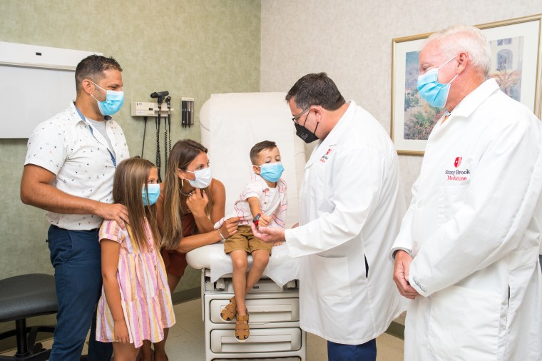 Four-year-old Charlie DeFraia, sitting center, is surrounded by his family, left, and some of the doctors who saved his life, right, including Dr. David Chesler and Dr. Richard Scriven of Stony Brook Medicine in New York.