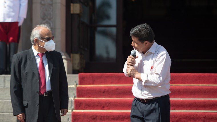 El presidente peruano, Pedro Castillo, habla a un micrófono mientras voltea a ver a un hombre de traje y corbata roja, Aníbal Torres, quien era el primer ministro en ese momento
