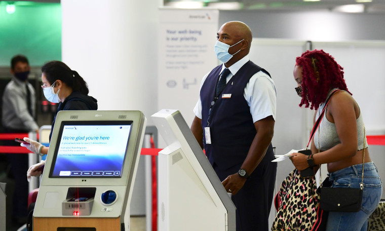Un empleado de American Airlines ayuda a los viajeros con la autofacturación en el Aeropuerto Internacional de Los Ángeles en Los Ángeles, California, en el 1 de octubre de 2020.