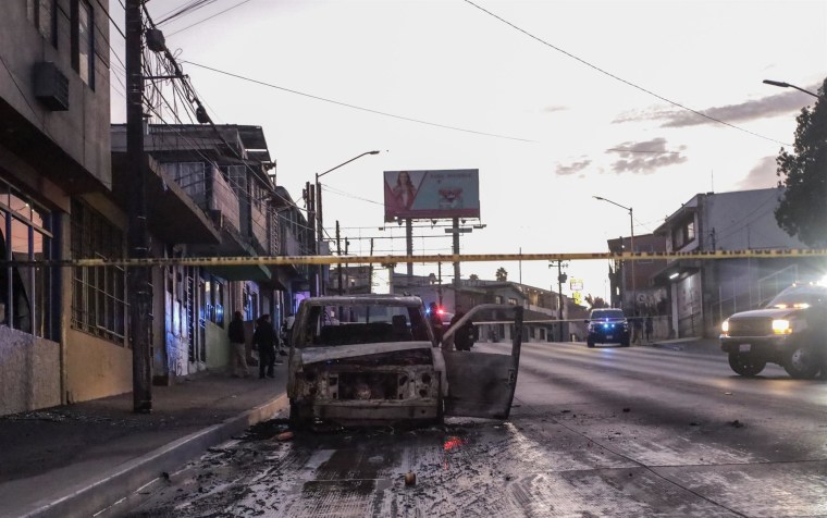 Policías acordonan la zona en donde se halló un vehículo incinerado en Tijuana, Baja California, México, el viernes 12 de agosto de 2022.