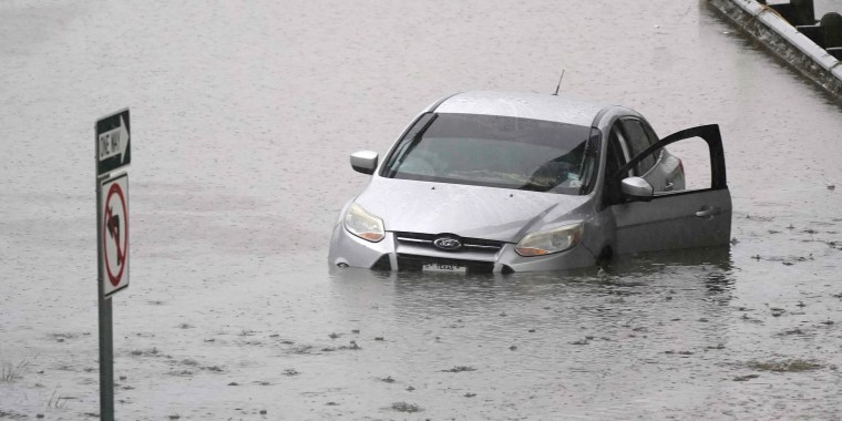 A car sits in flood waters covering a closed highway in Dallas on Aug. 22, 2022.