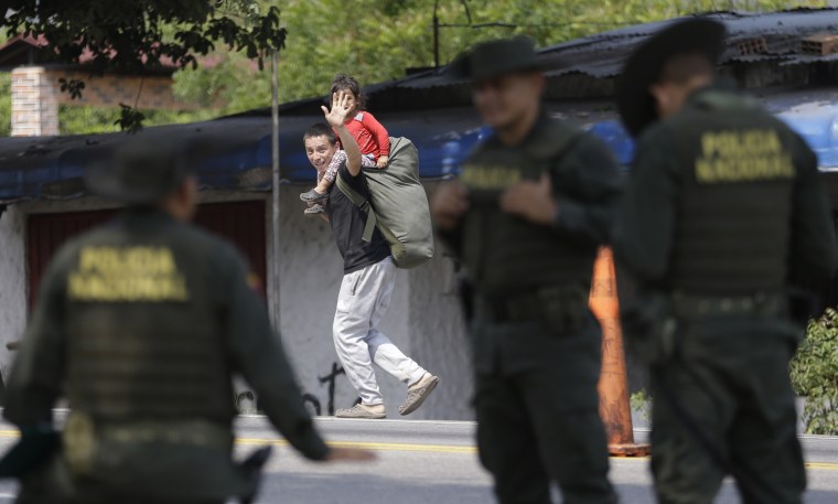 A Venezuelan migrant waves at Colombian polic