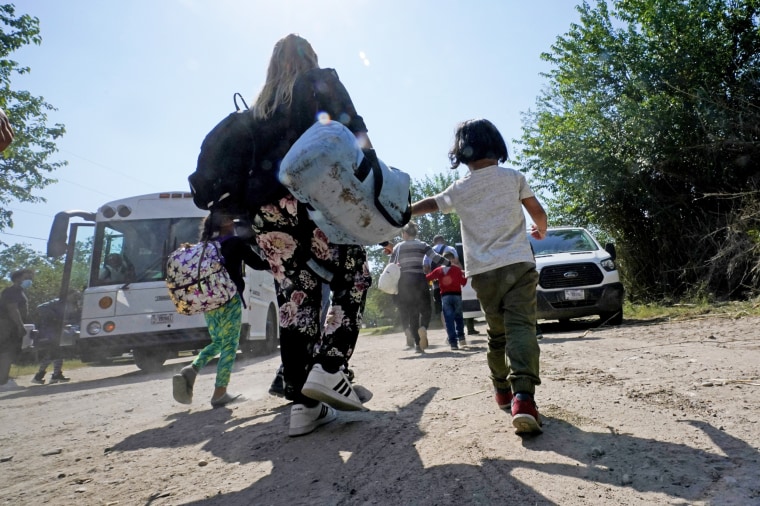 A migrant family from Venezuela move to a Border Patrol transport vehicle